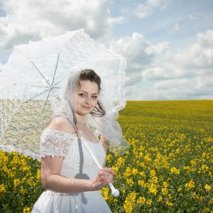 Mariée avec son umbrelle dans un champs de colza